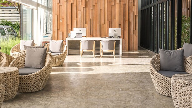 Ein modernes Interieur mit Holzwandverkleidung, gewebten Deckenleuchten und Korbmöbeln.