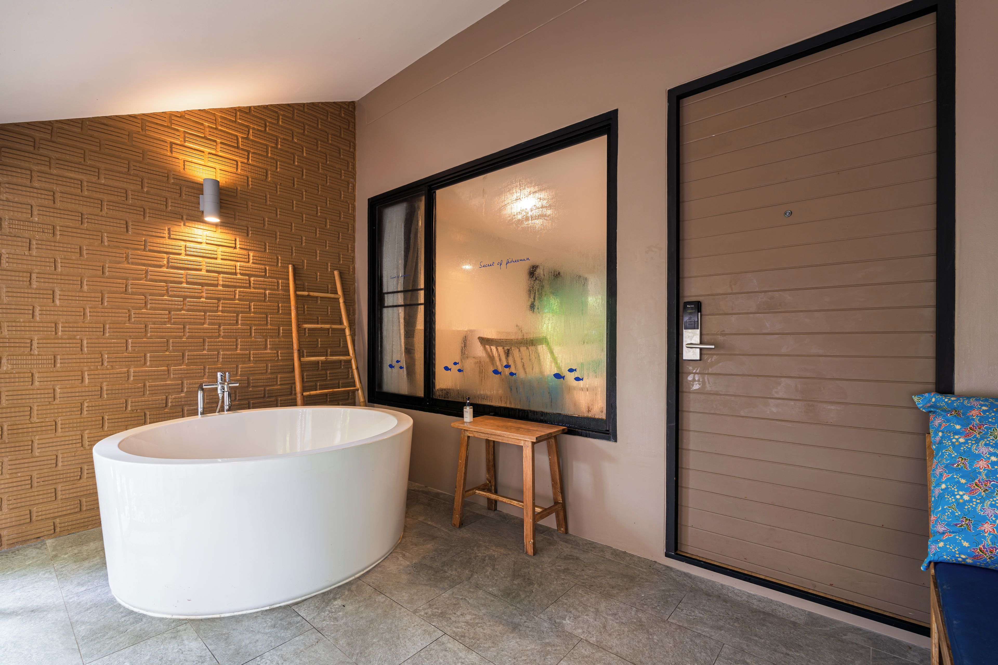 A modern bathroom with a freestanding bathtub, a wooden ladder, and a large window with a view of a green landscape.