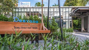 A sign for Deevana Krabi Resort with Thai script, surrounded by greenery.