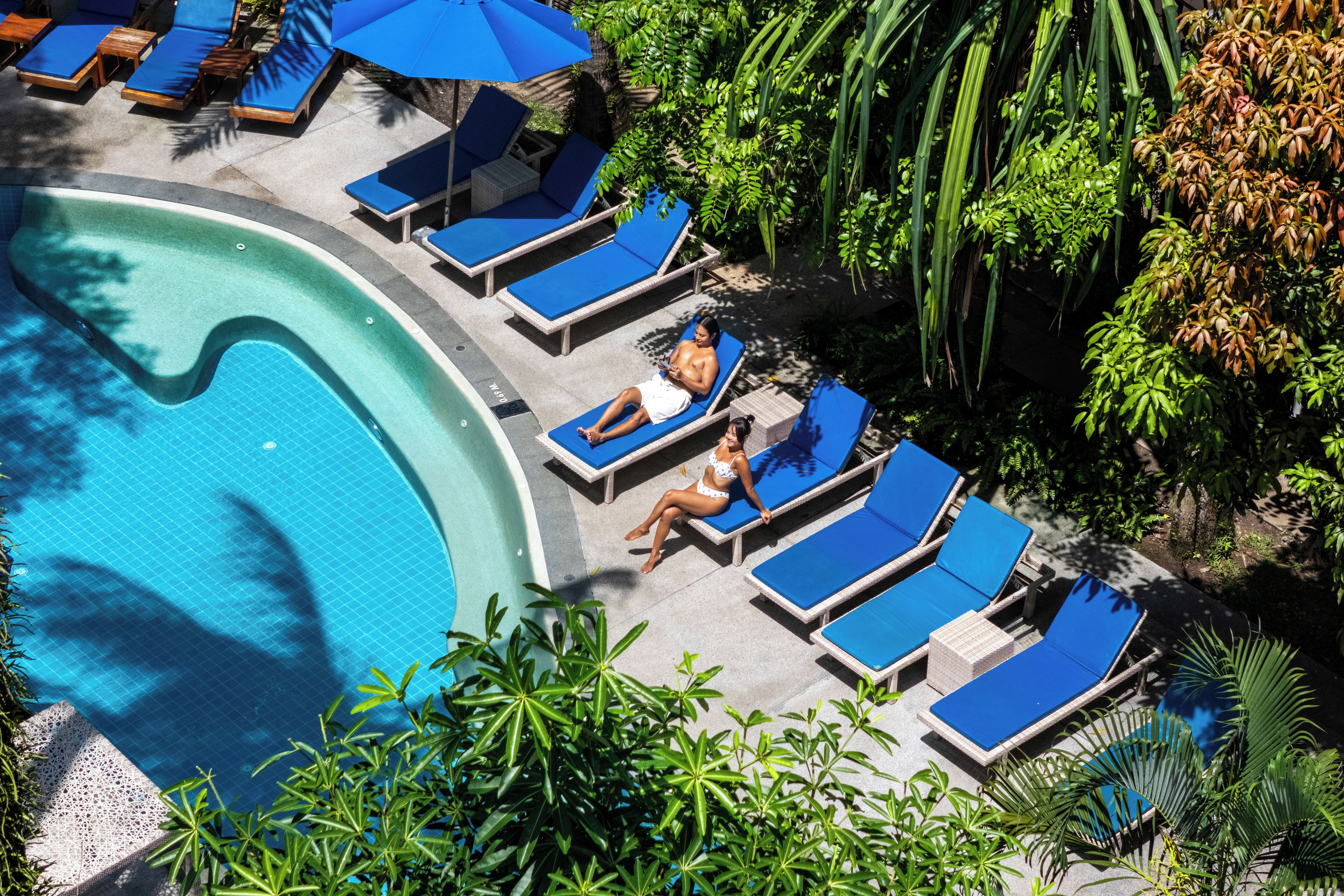 Un área de piscina con sillones de descanso y sombrillas.
