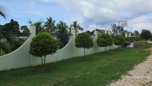 A gated property with a curved wall, small trees, and a sign for 'Car Share'. - Oasi Fiore Bed and Breakfast (Dauis)