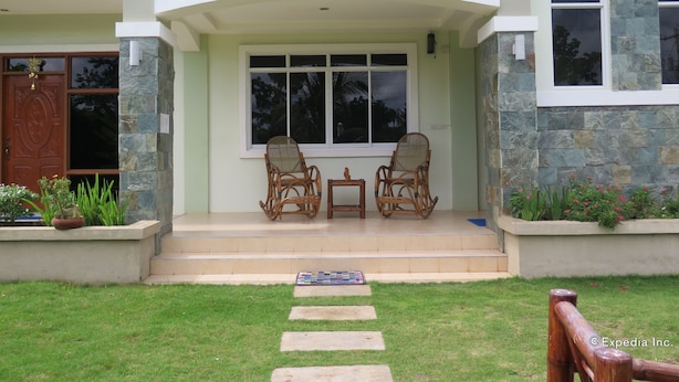 A house with a stone facade, a front porch with two wicker chairs and a small table, and a clear view of the front door. - Oasi Fiore Bed and Breakfast (Dauis)