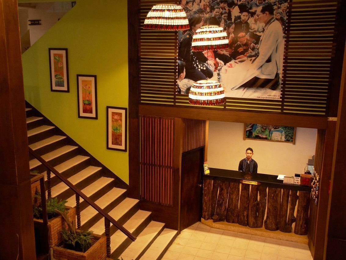 A hotel lobby with a staircase, a reception desk, and framed artwork on the walls.