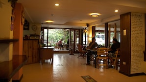 L’intérieur d’un restaurant, avec des meubles en bois, une horloge et un panneau affichant le menu.