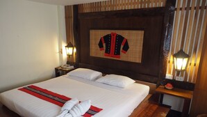 Une chambre d’hôtel avec un grand lit, deux tables de chevet, une lampe fixée au mur et un objet décoratif accroché au mur.