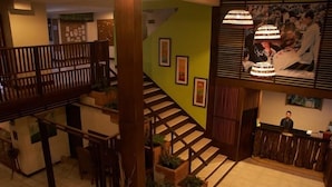 Un hall d’hôtel avec un escalier, des rampes en bois et un comptoir d’accueil.