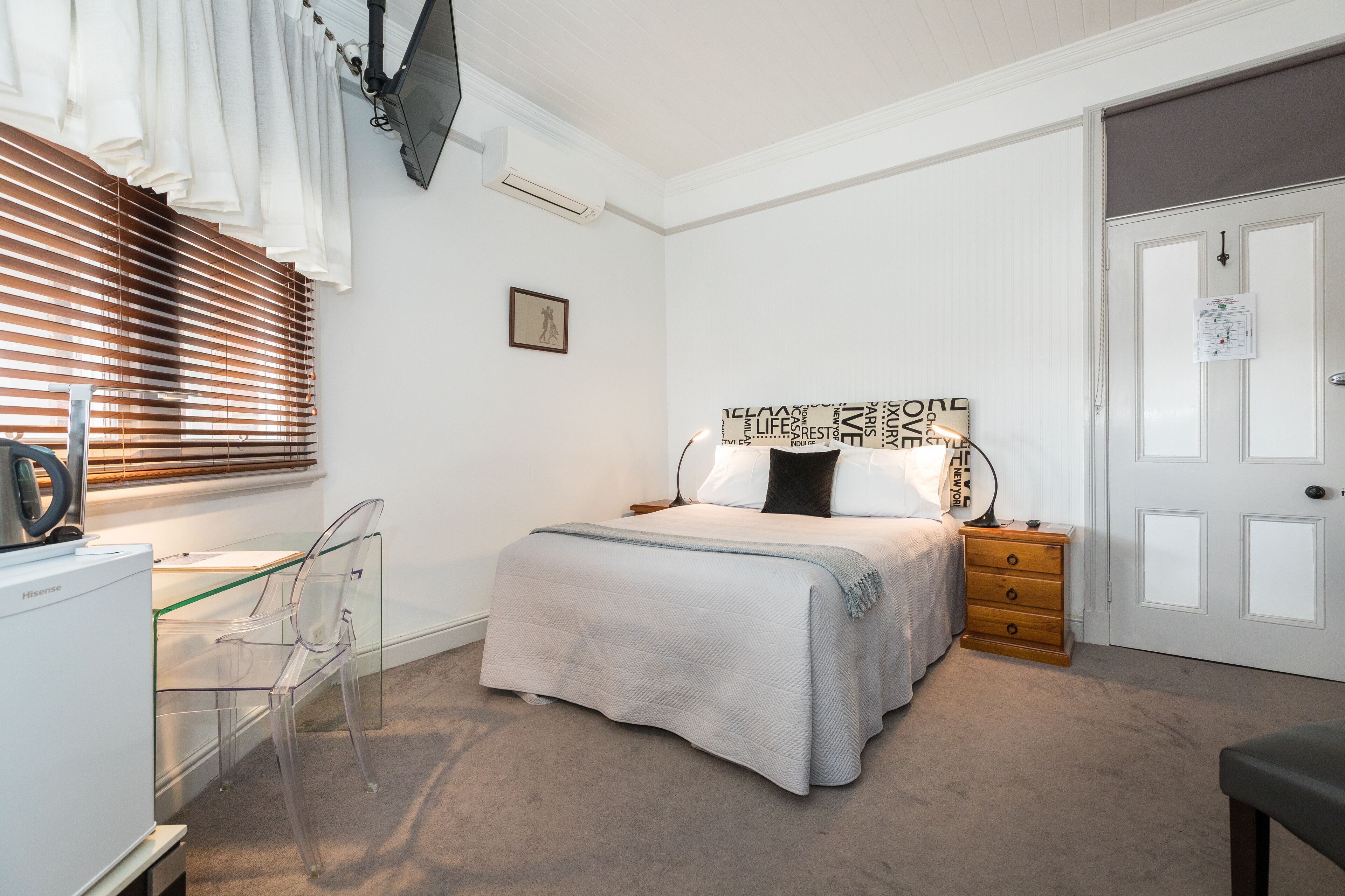 Un dormitorio con cama, mesita de noche, cómoda y escritorio con silla.