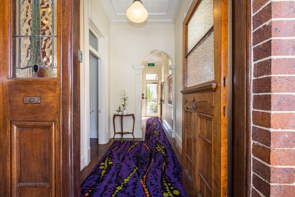 Un pasillo con alfombra estampada, puertas de madera y pared de ladrillo.