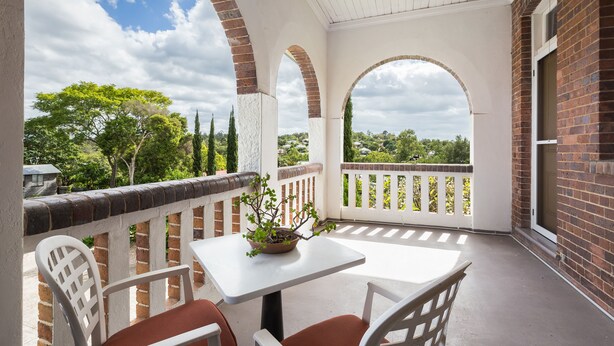Un patio techado con una mesa y sillas, paredes de ladrillo y vistas a zonas verdes.