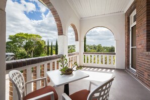 Un patio techado con una mesa y sillas, paredes de ladrillo y vistas a zonas verdes.