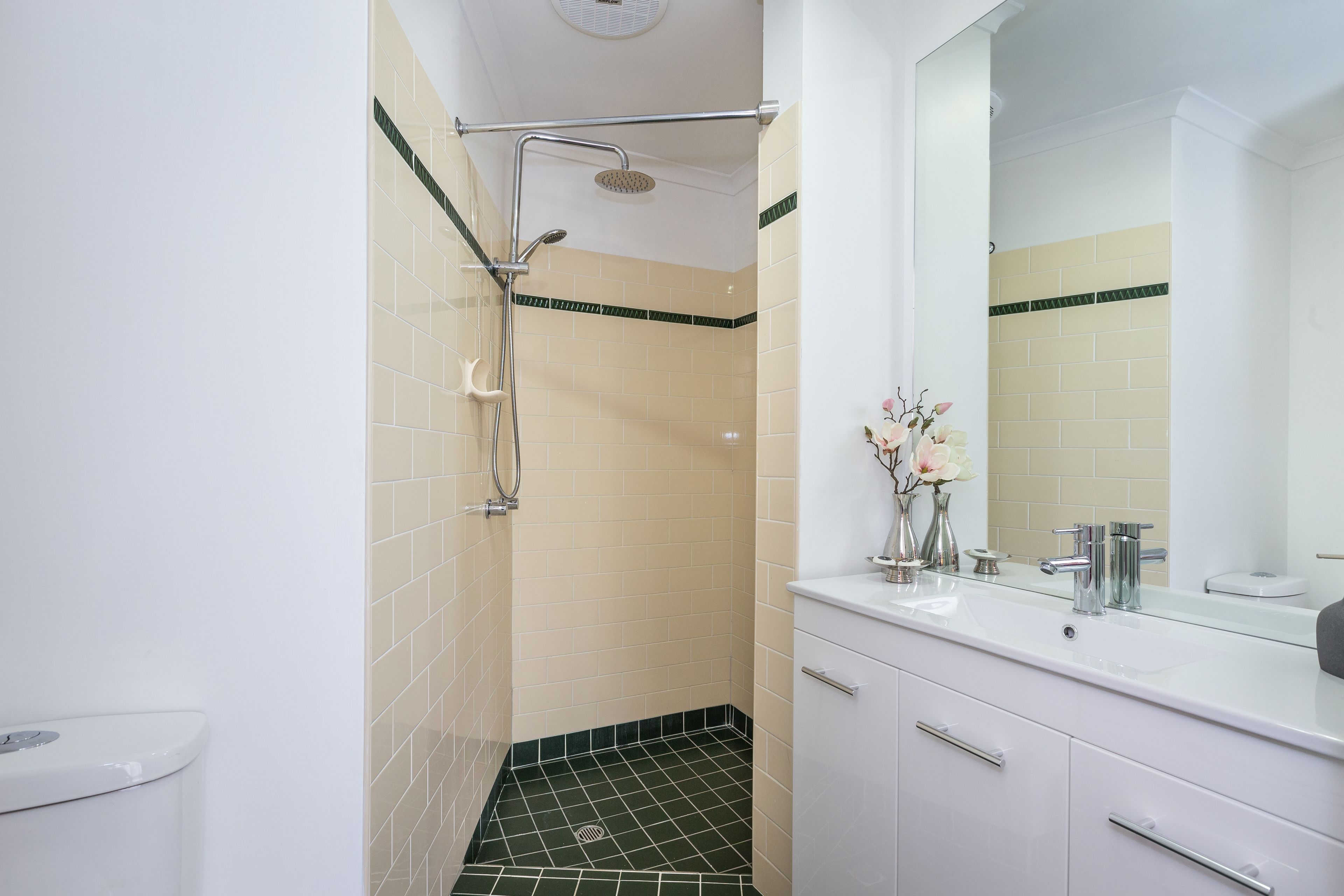 Een moderne badkamer met douche, toilet, wastafel en spiegel.