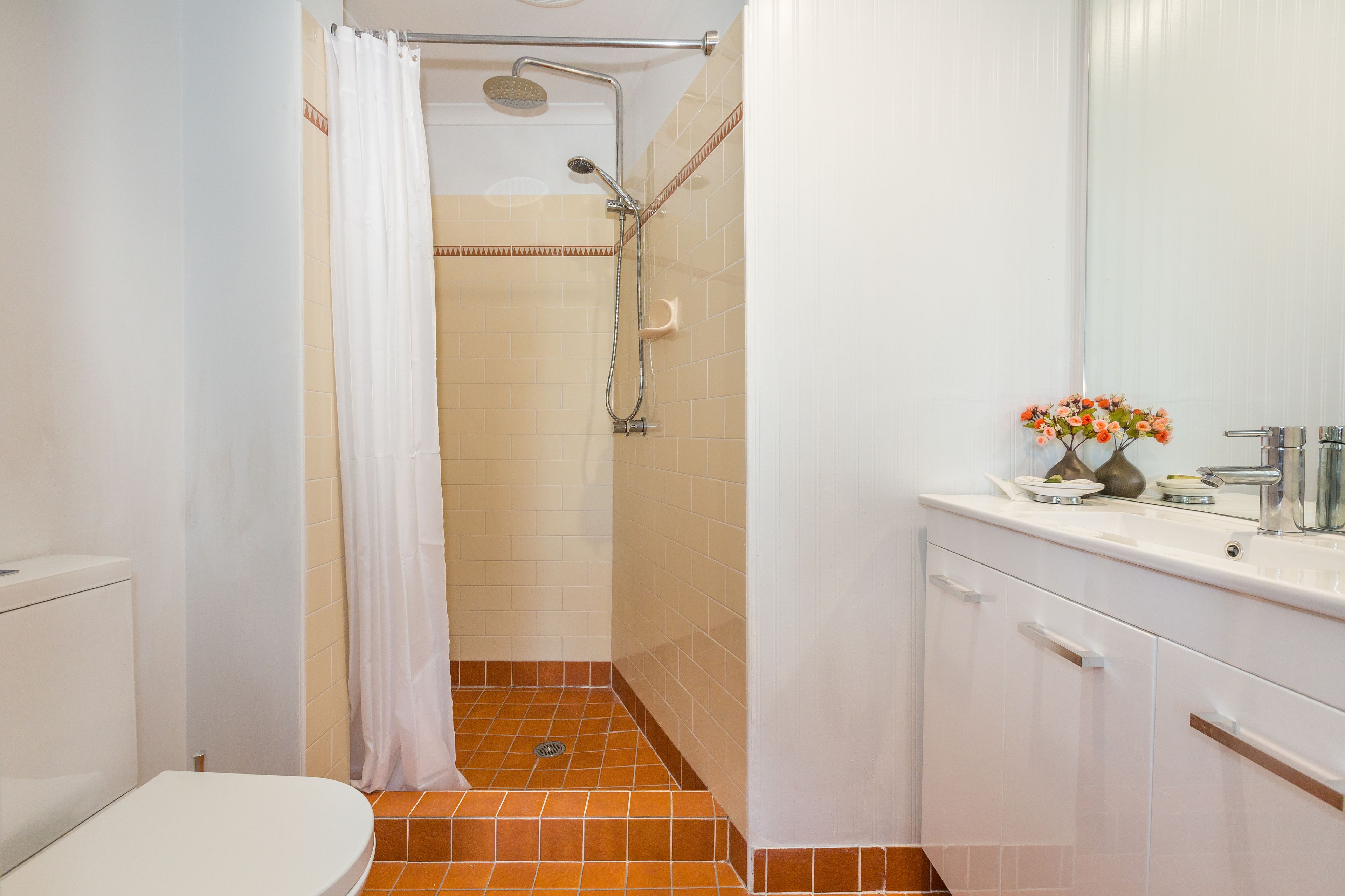 Une salle de bain équipée d’une douche, de toilettes et d’un lavabo avec un miroir.