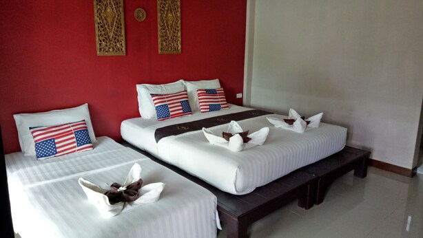 A hotel room with two beds, red walls, and American flag pillows.