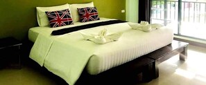 A neatly made bed with white linens, two pillows with a Union Jack design, and a black throw blanket.