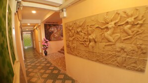 A hallway with patterned flooring, a floral arrangement, and a relief sculpture on the wall. - Suansin Art Garden (Lam Luk Ka)