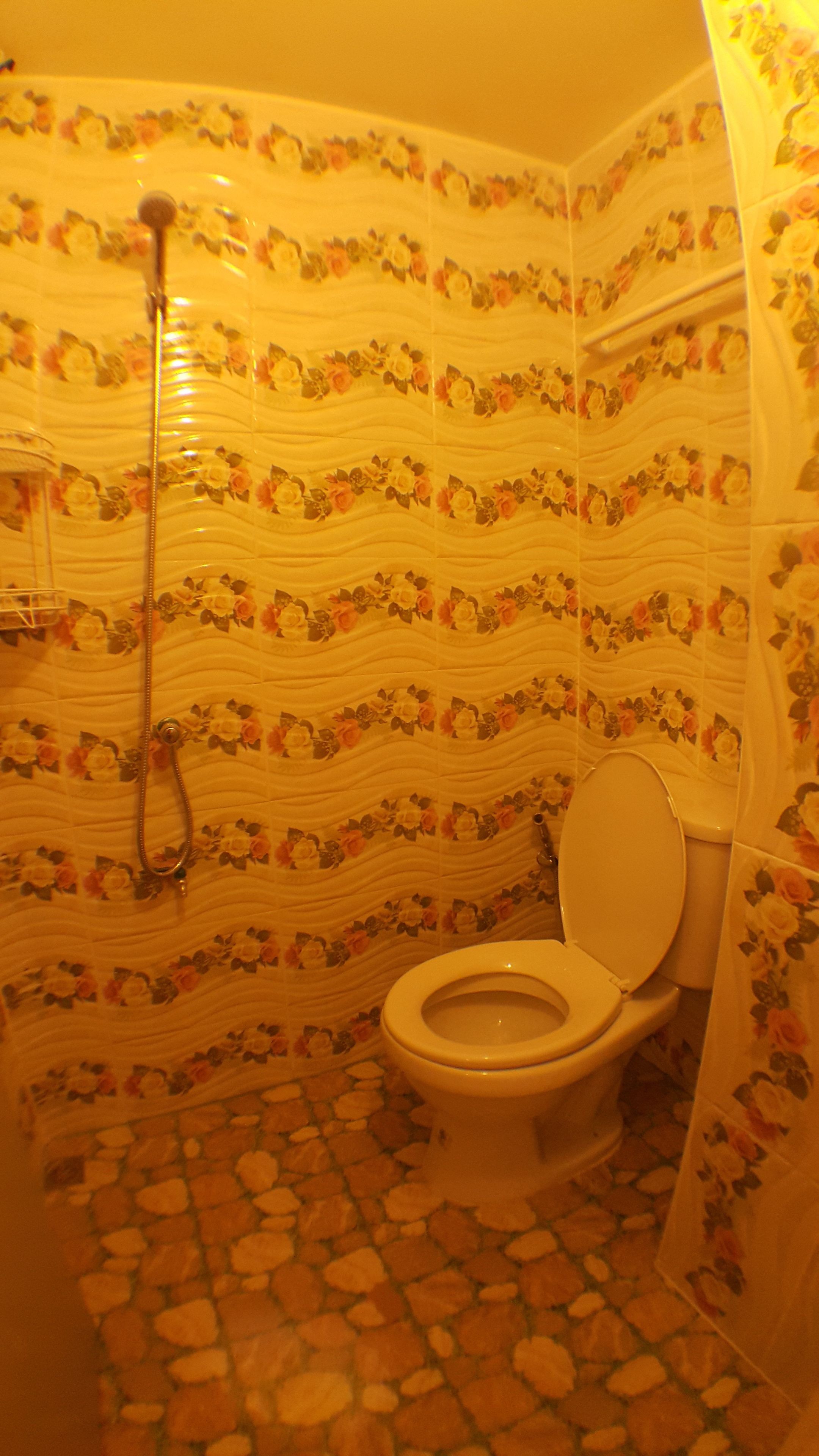 A bathroom with a toilet, shower, and floral patterned walls.