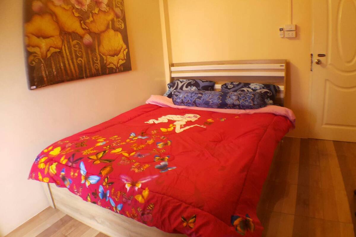 A bedroom with a bed, a nightstand, a door, and a wall-mounted painting.