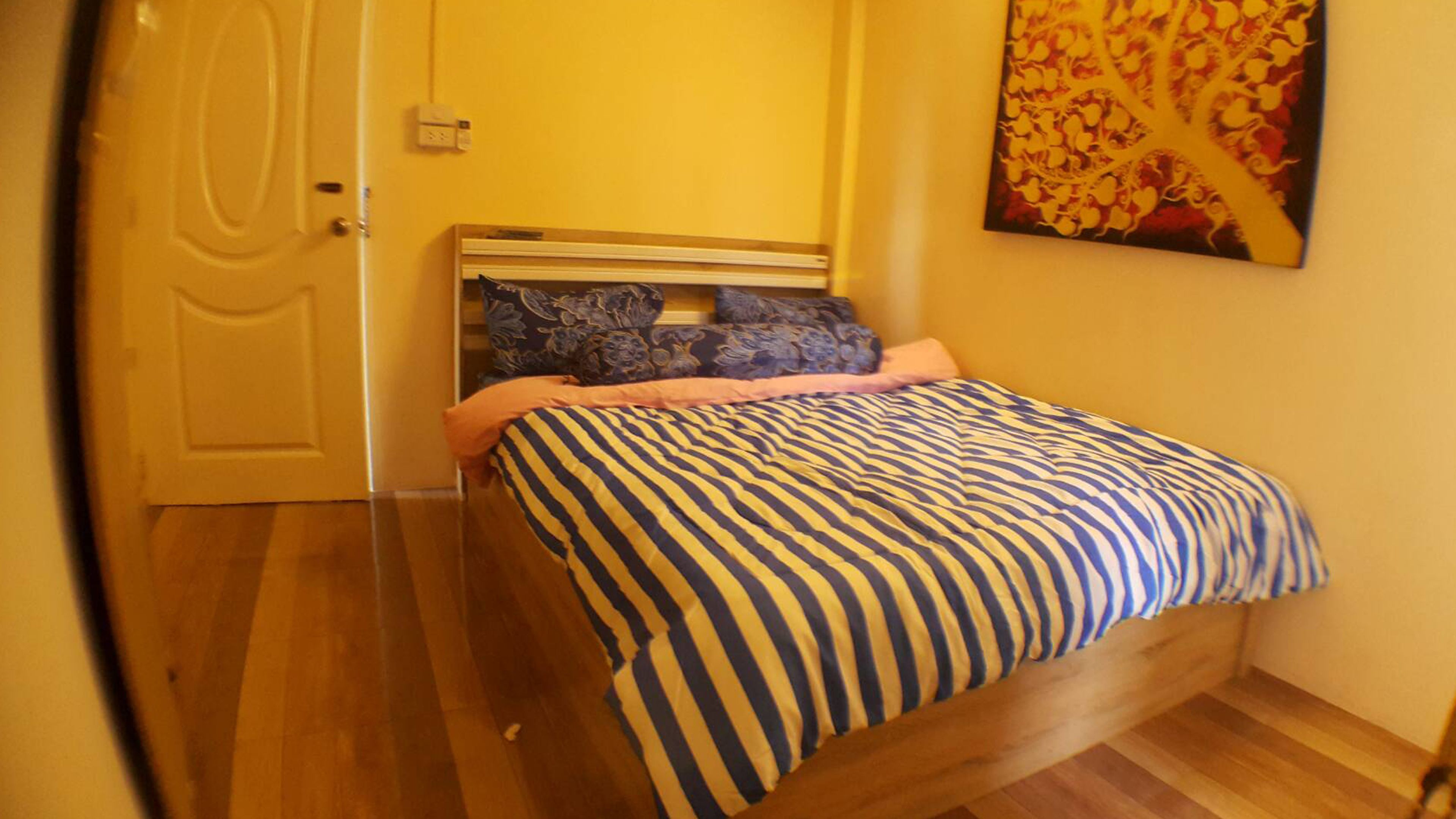 A bedroom with a bed, a door, and a wall-mounted painting.