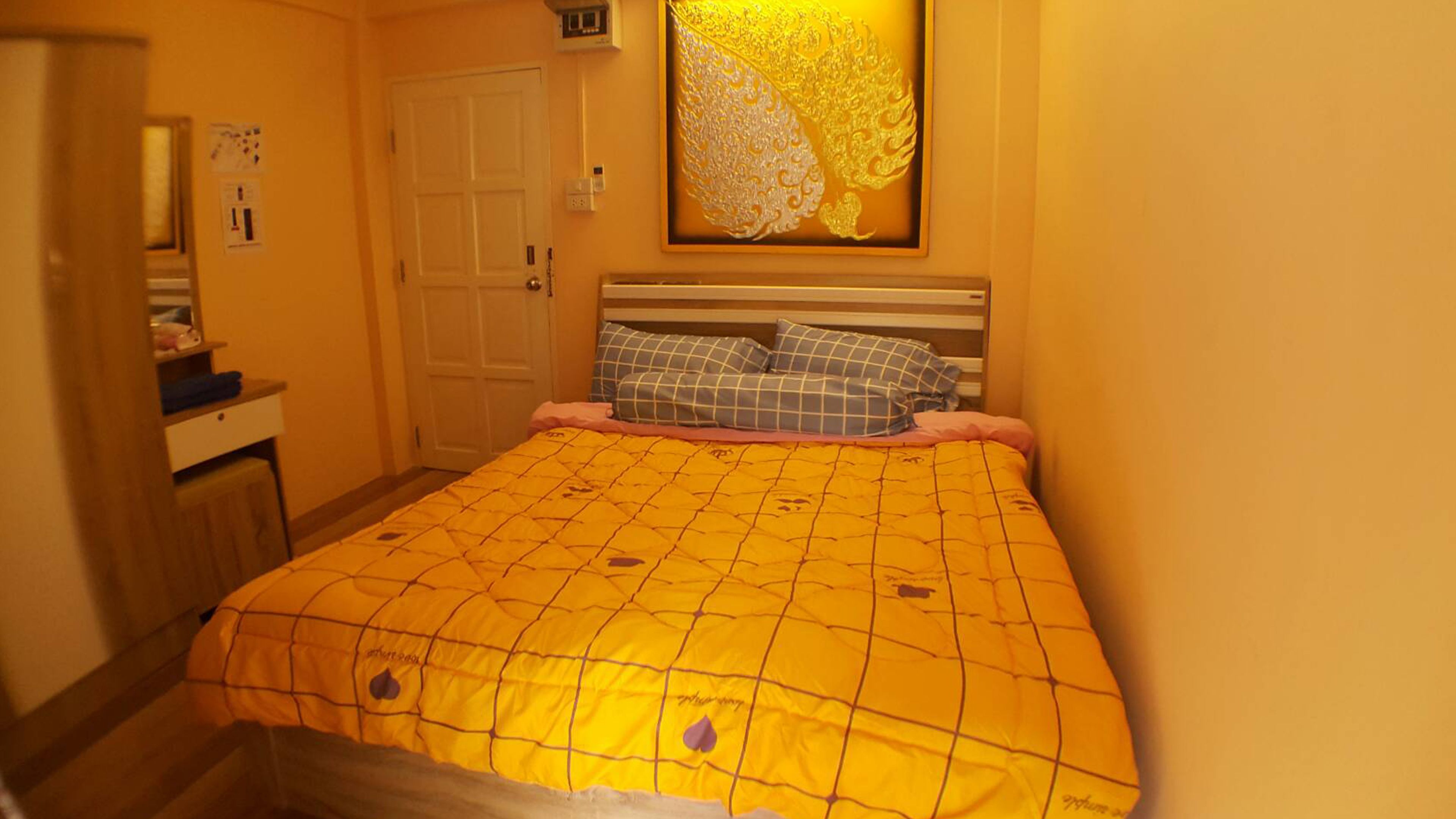 A bedroom with a bed, a nightstand, a dresser, and a door.