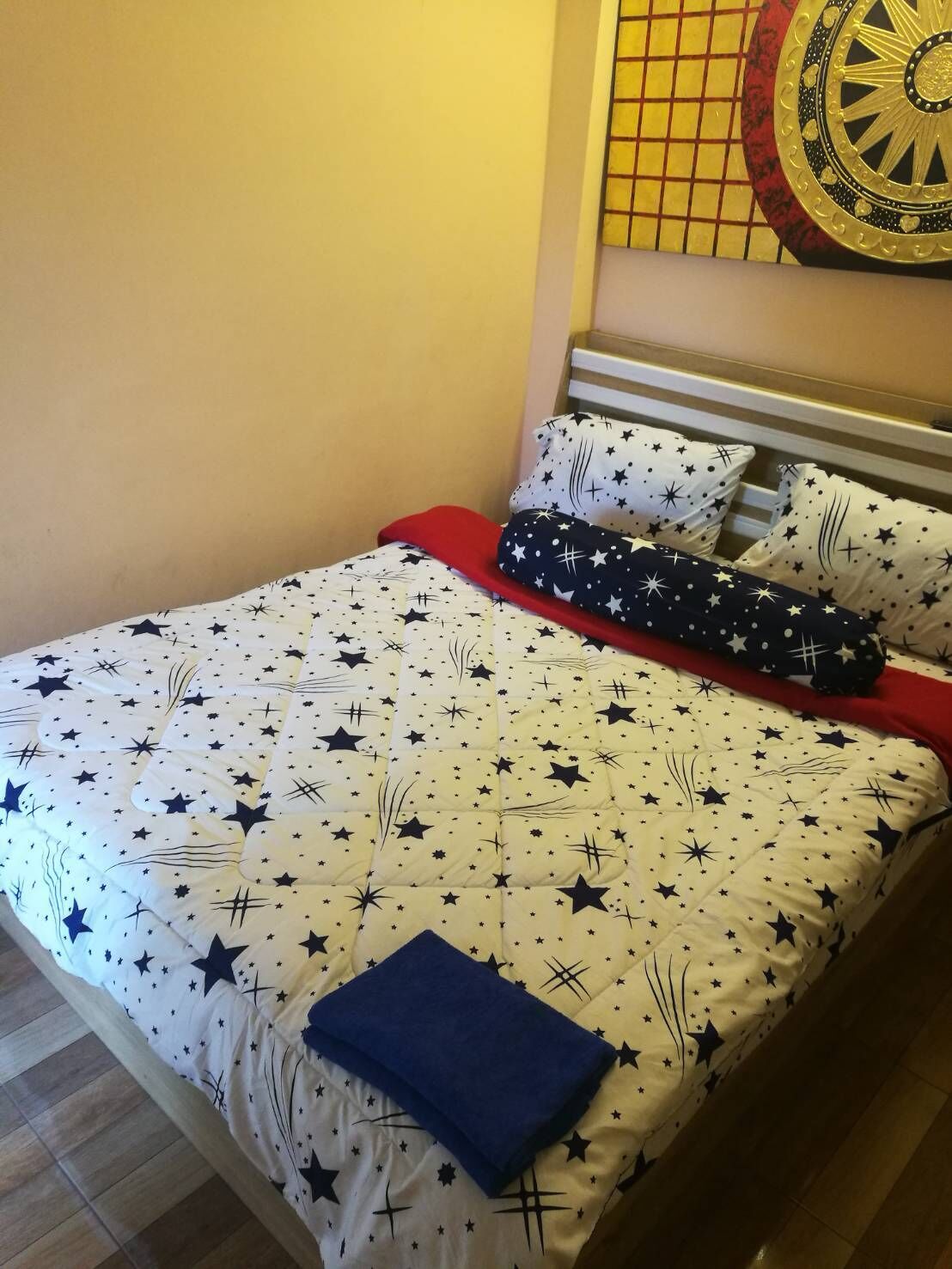 Una cama con un edredón estampado con estrellas, dos almohadas y una manta azul.