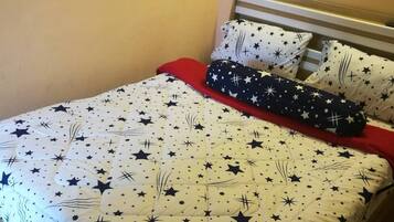 Una cama con un edredón estampado con estrellas, dos almohadas y una manta azul.