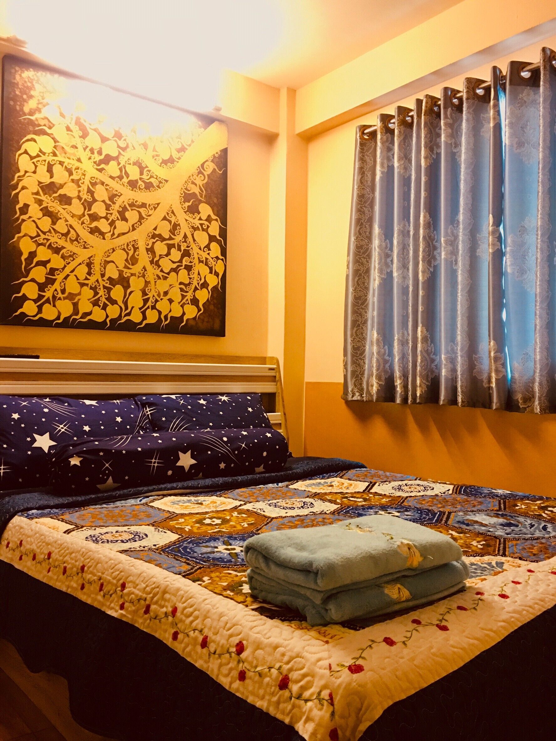 A bedroom with a bed, a large wall painting, and a window with curtains.