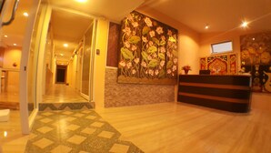 A hotel reception area with a reception desk, a large floral mural on the wall, and a patterned floor. - Suansin Art Garden (Lam Luk Ka)
