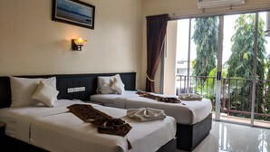 A hotel room with two beds, a large window with a view of greenery, an air conditioning unit, and a framed picture on the wall. - Kanokan Hotel (Kanchanaburi)