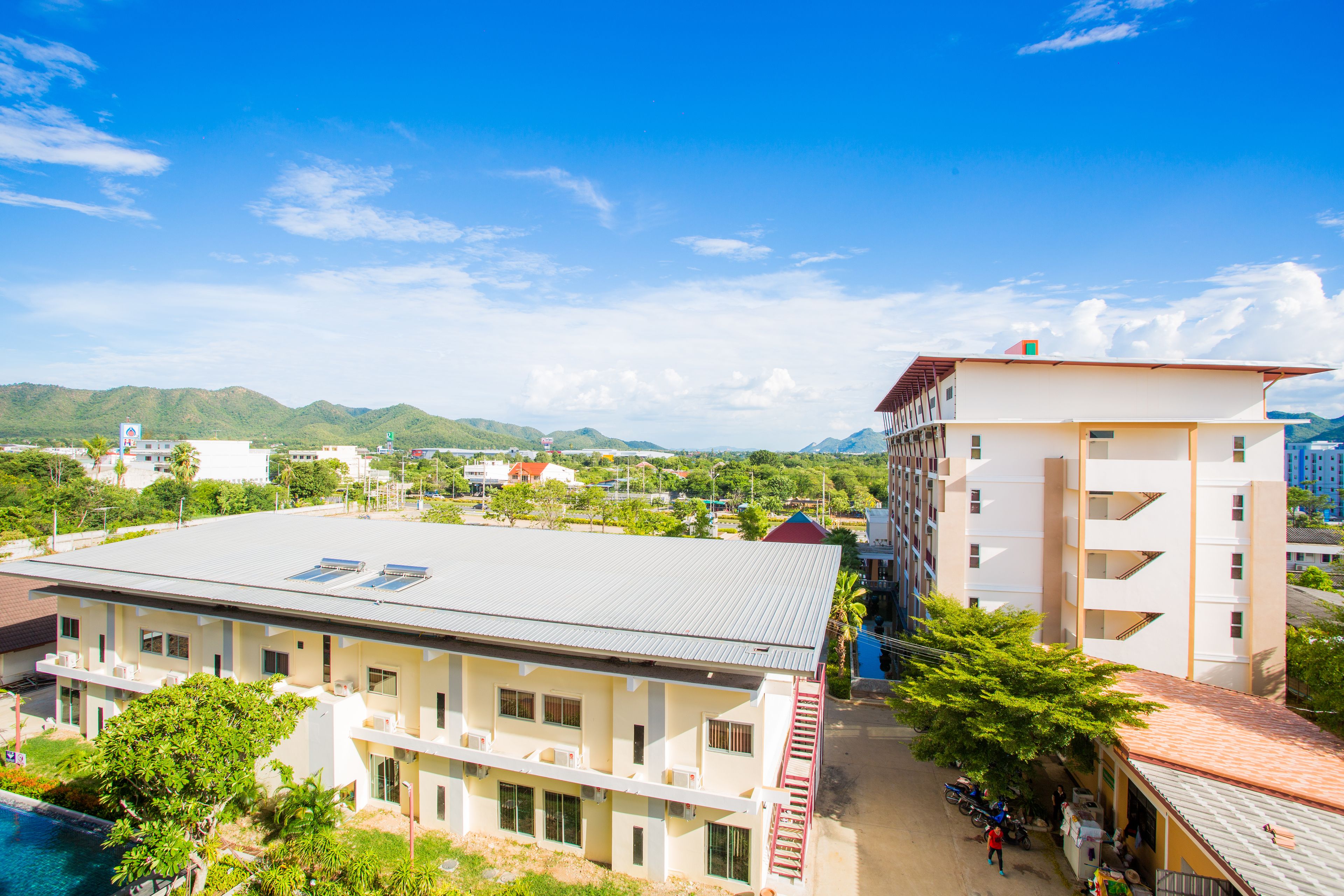 A hotel with a flat roof, multiple floors, and a swimming pool.