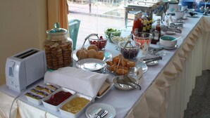 A buffet table with various food items, condiments, and utensils. - Kanokan Hotel (Kanchanaburi)