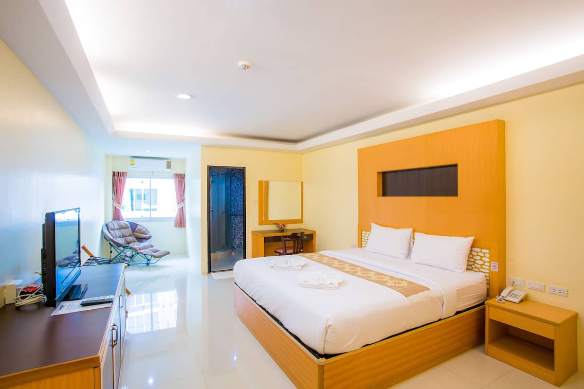 A hotel room with a bed, desk, chair, and a small table with a phone.