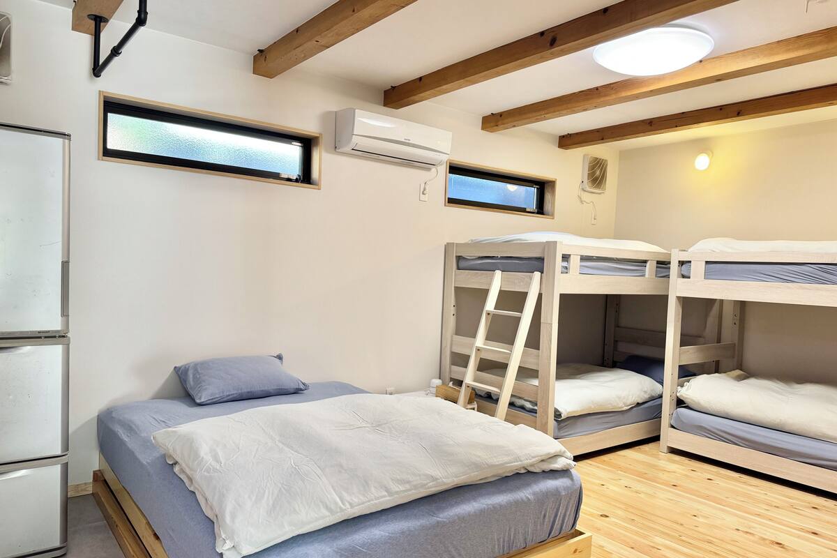 Dormitorio con literas, una escalera, un ventanal y un equipo de aire acondicionado.