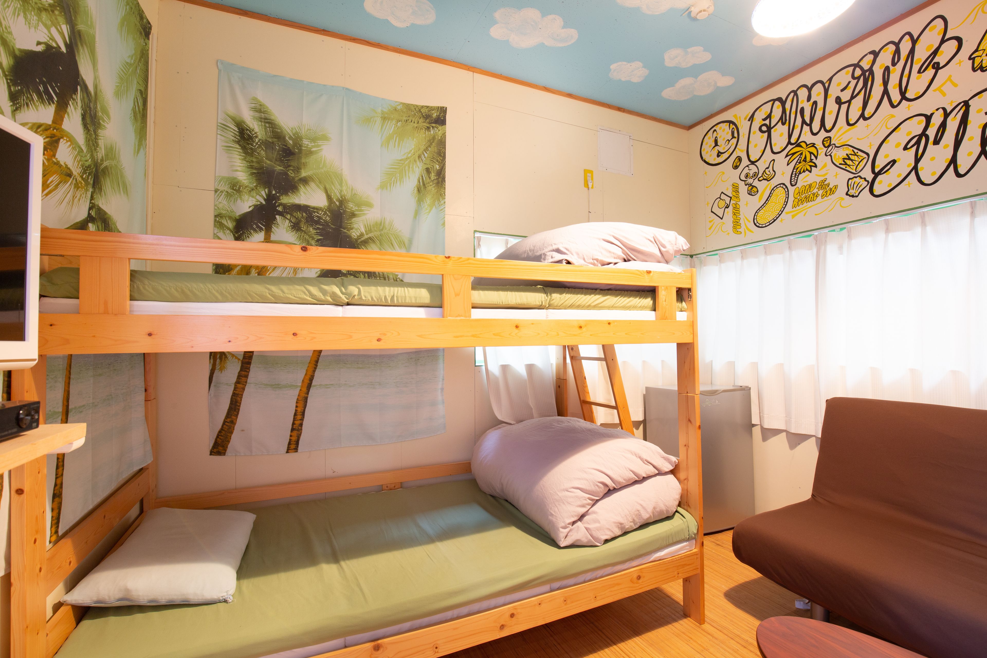 A bunk bed room with a wooden frame, a green mattress, and a brown sofa.
