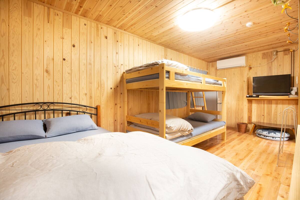 Una habitación tipo cabaña de madera con literas, televisor y una cama para mascotas.