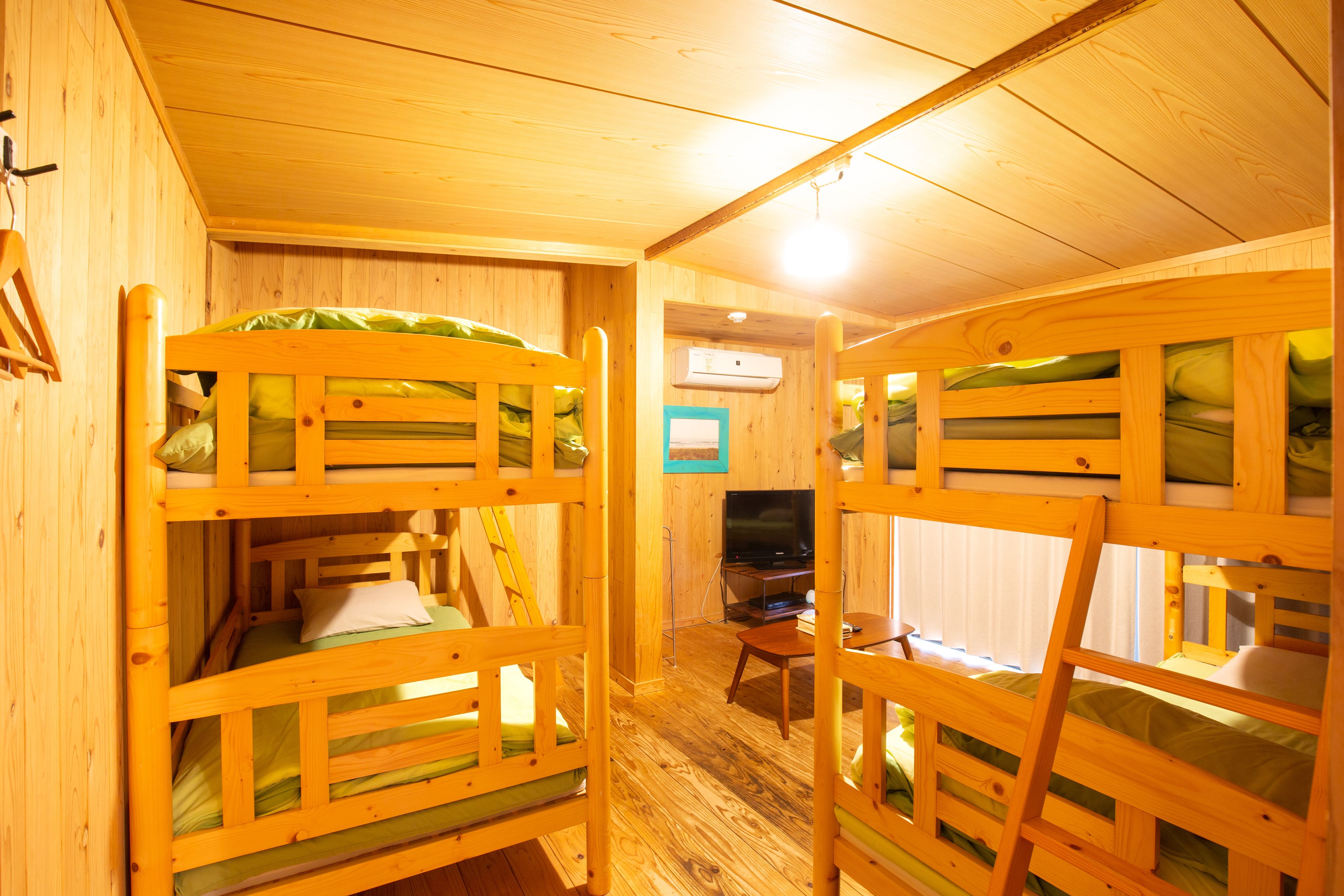 A room with bunk beds, a television, and a small table.