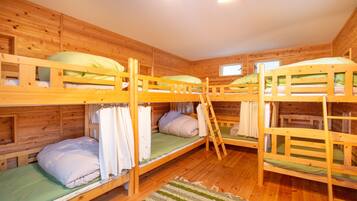 Une cabine avec trois lits superposés, des murs en bois et une fenêtre.
