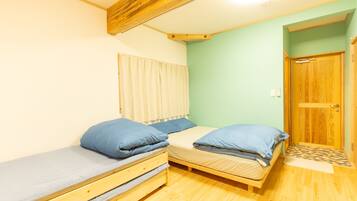 A small room with two wooden bunk beds, a window with blinds, and a wooden door.