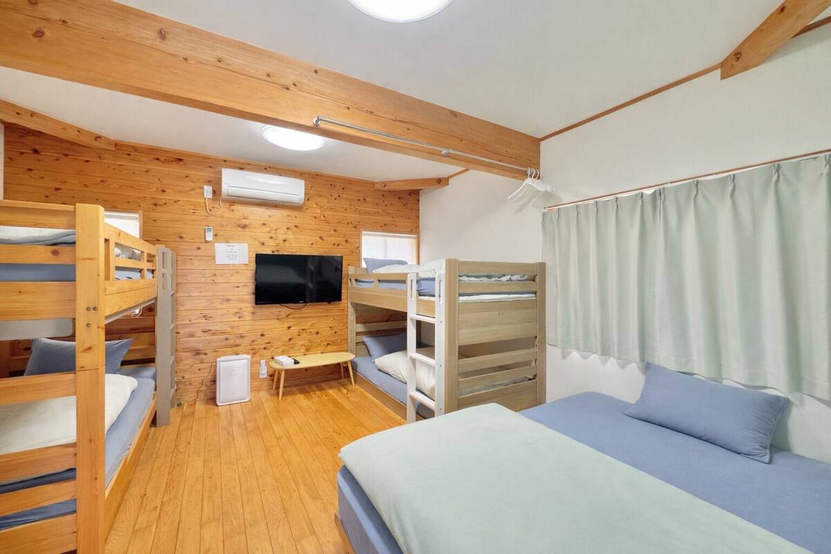 Habitación con literas, televisión, paredes de madera y ventana.