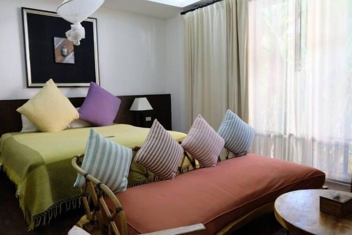 Quarto de hotel com cama, sofá, mesa redonda e luminária.