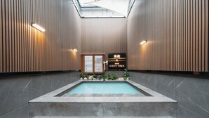 A modern hotel interior with a pool, wooden panel walls, and a sign indicating the hotel name. - CozyTree Hotel (Busan)