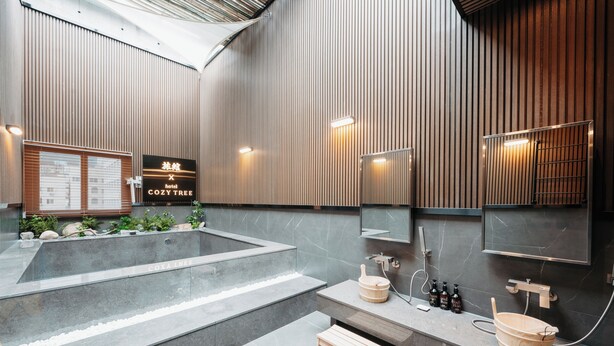 A modern hotel bathroom with a large bathtub, wooden accents, and a vanity with a sink and mirror. - CozyTree Hotel (Busan)