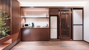 A compact kitchen with a microwave, coffee maker, and a refrigerator. - CozyTree Hotel (Busan)