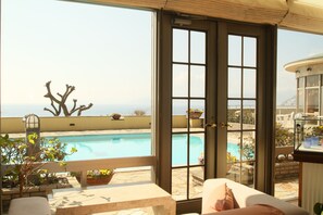 Et værelse med udsigt til et poolområde og en balkon med udendørs møbler.
