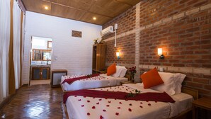 A hotel room with two beds, wooden flooring, brick walls, and a small kitchenette in the background. - Teak Wood Hotel (Nyaungshwe)