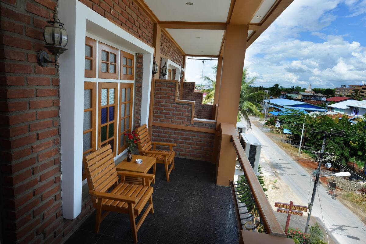 A balcony with wooden furniture and a brick wall.