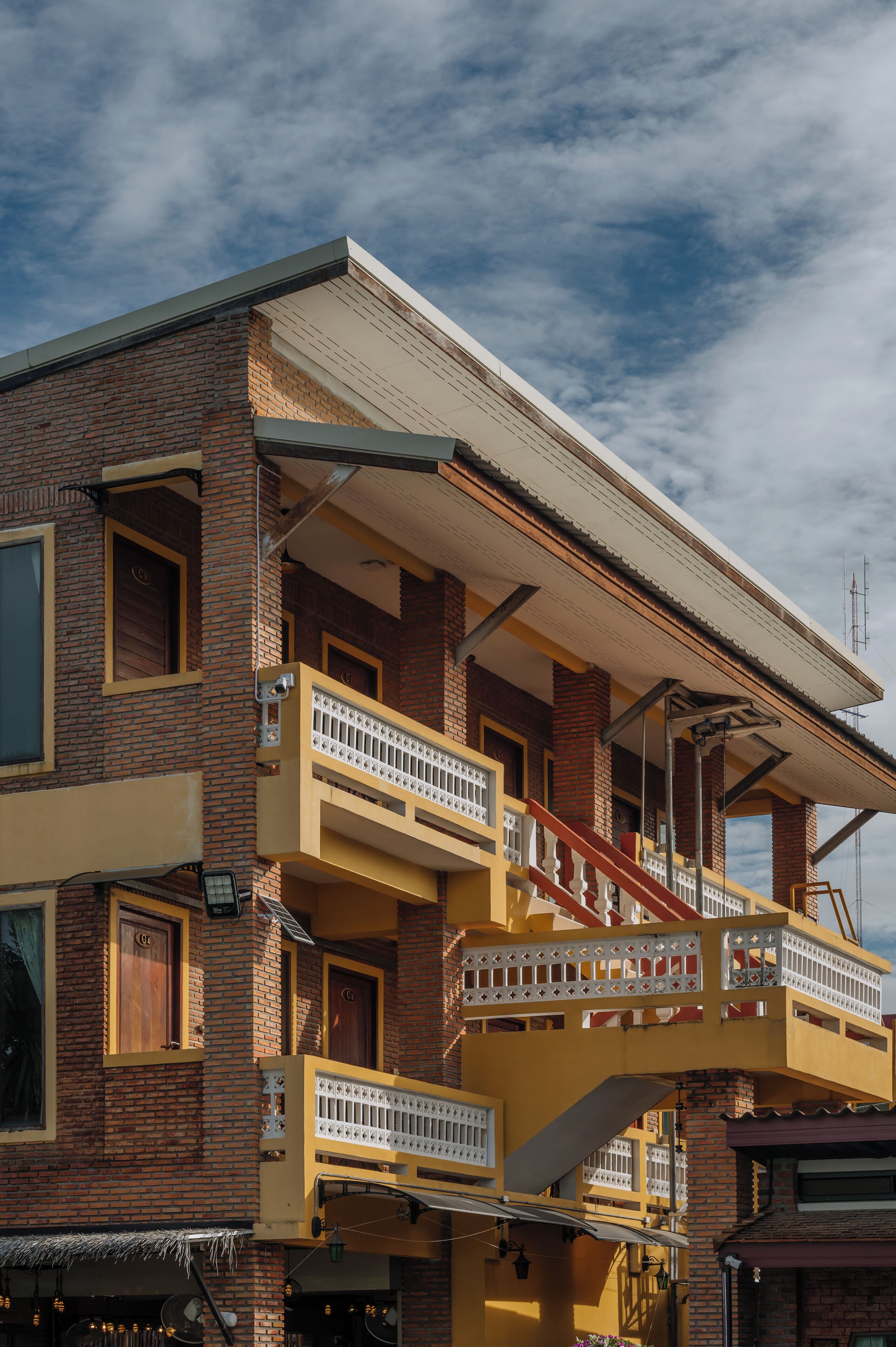 A multi-story building with a yellow facade, multiple balconies, and a flat roof.