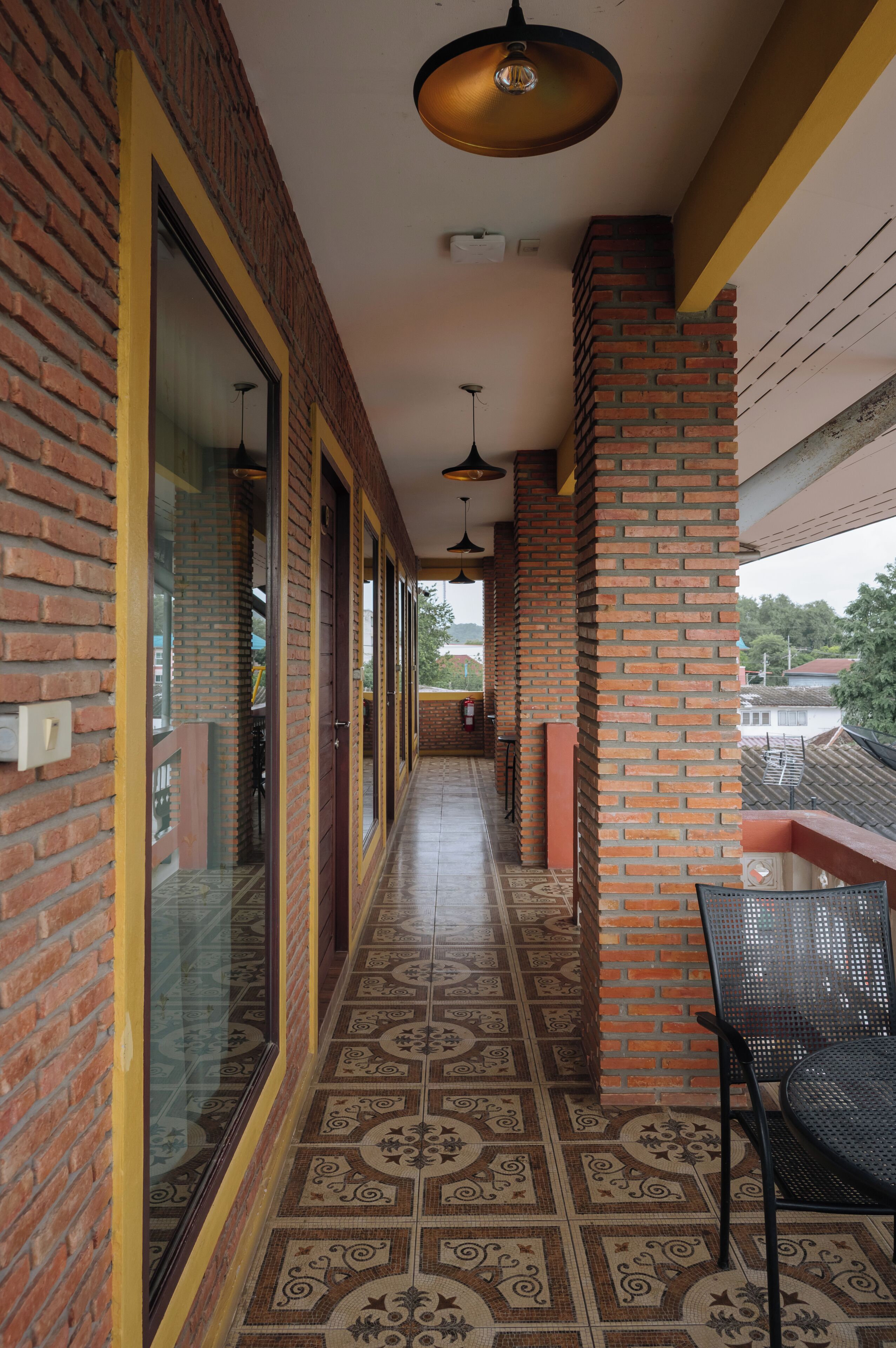 A corridor with patterned flooring, brick walls, and a metal chair.