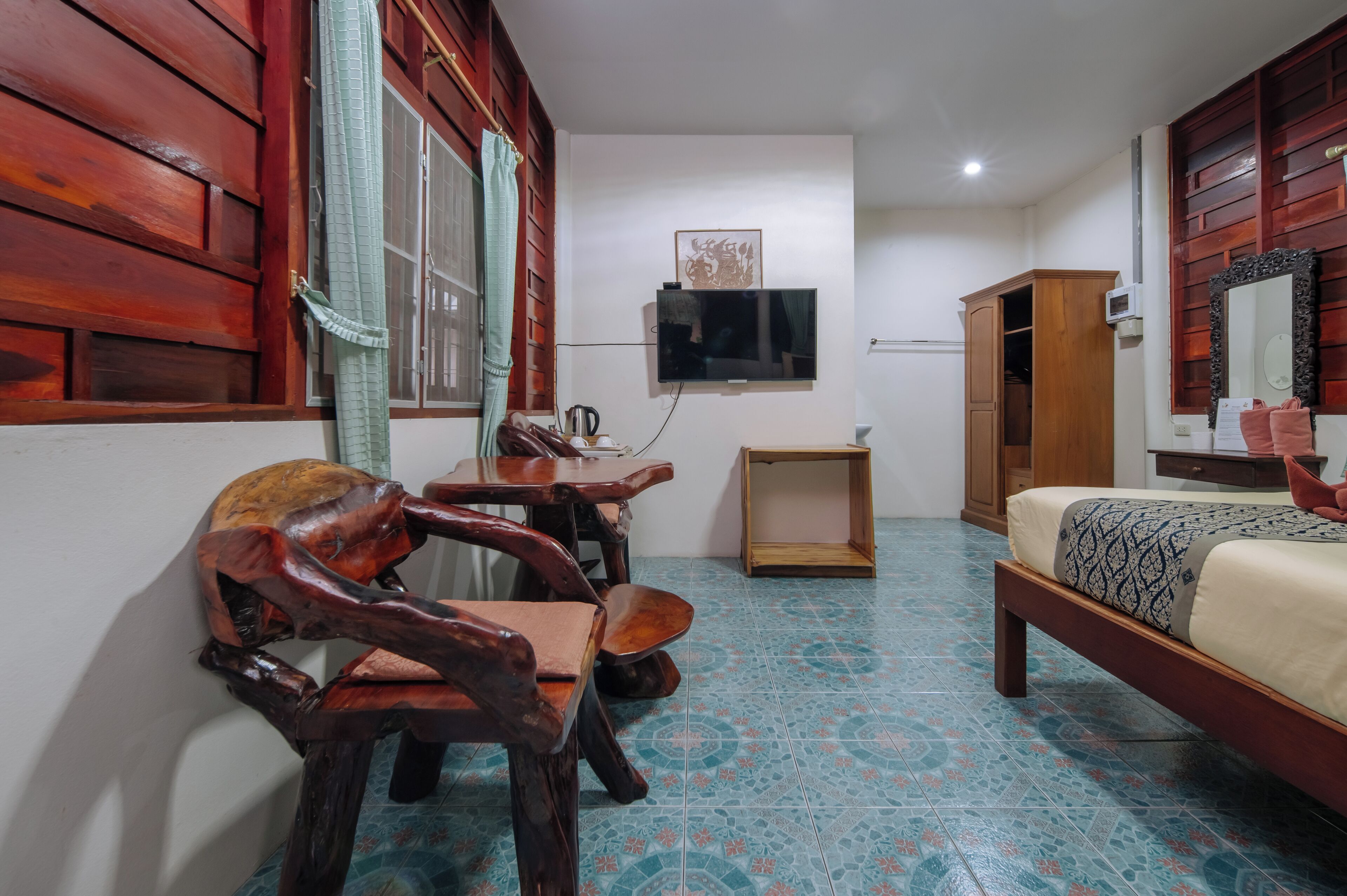 Une chambre avec un lit, des meubles en bois, une télévision et un sol carrelé.