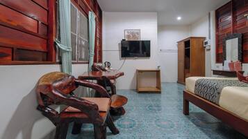 Una habitación con cama, muebles de madera, televisor y piso de baldosas.