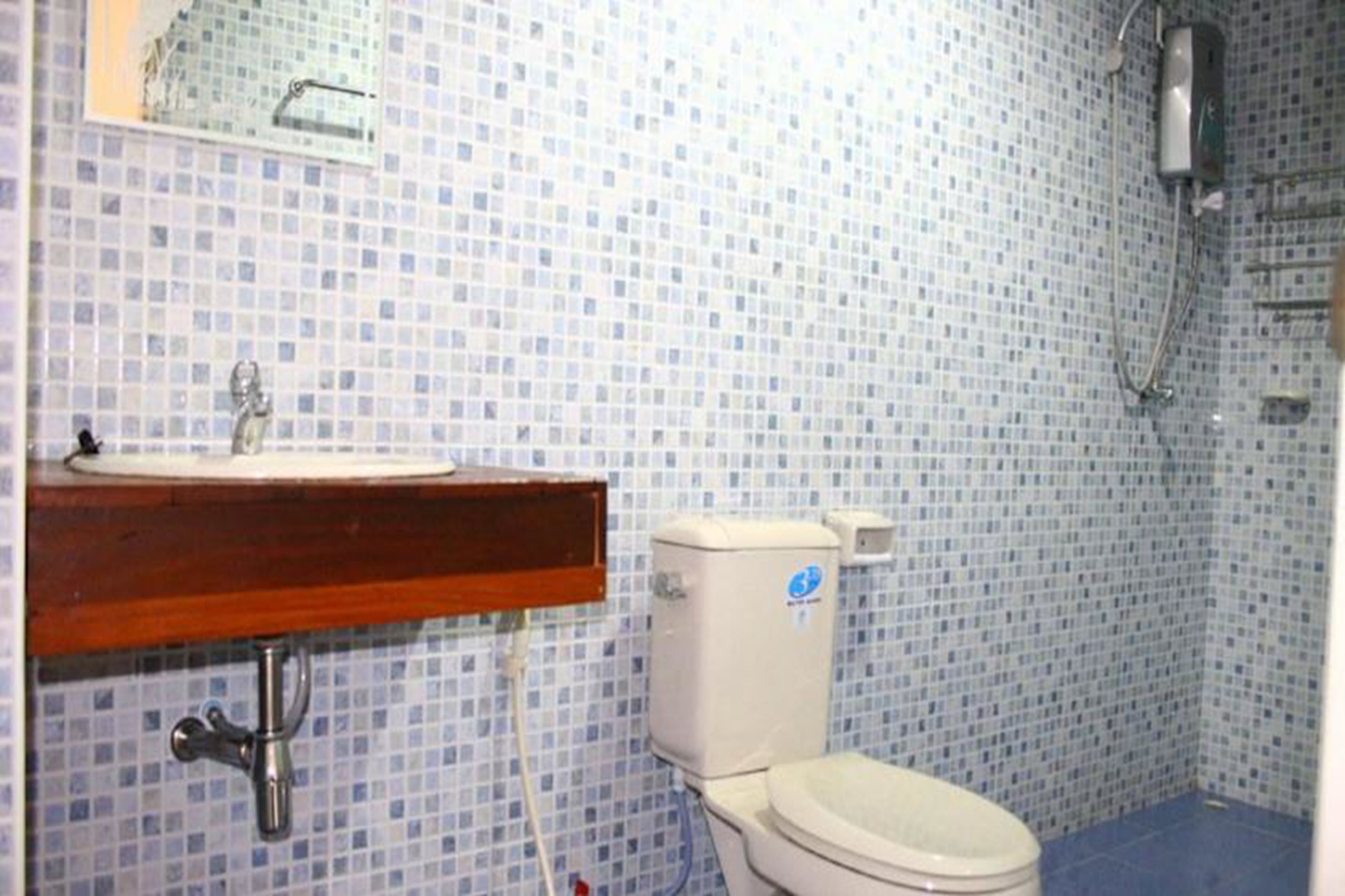 A bathroom with a tiled floor, a sink, a toilet, and a shower.